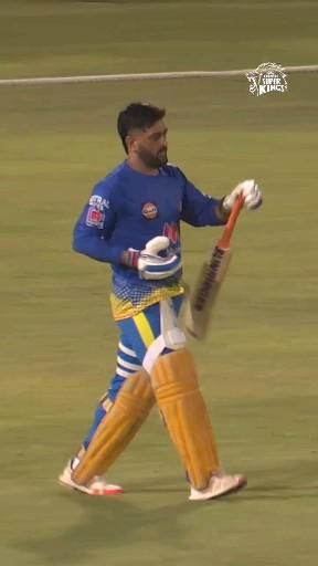 a man in blue and yellow uniform holding a baseball bat while walking across a field