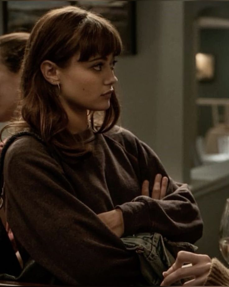 two women sitting at a table with wine glasses in front of them and one woman standing behind her