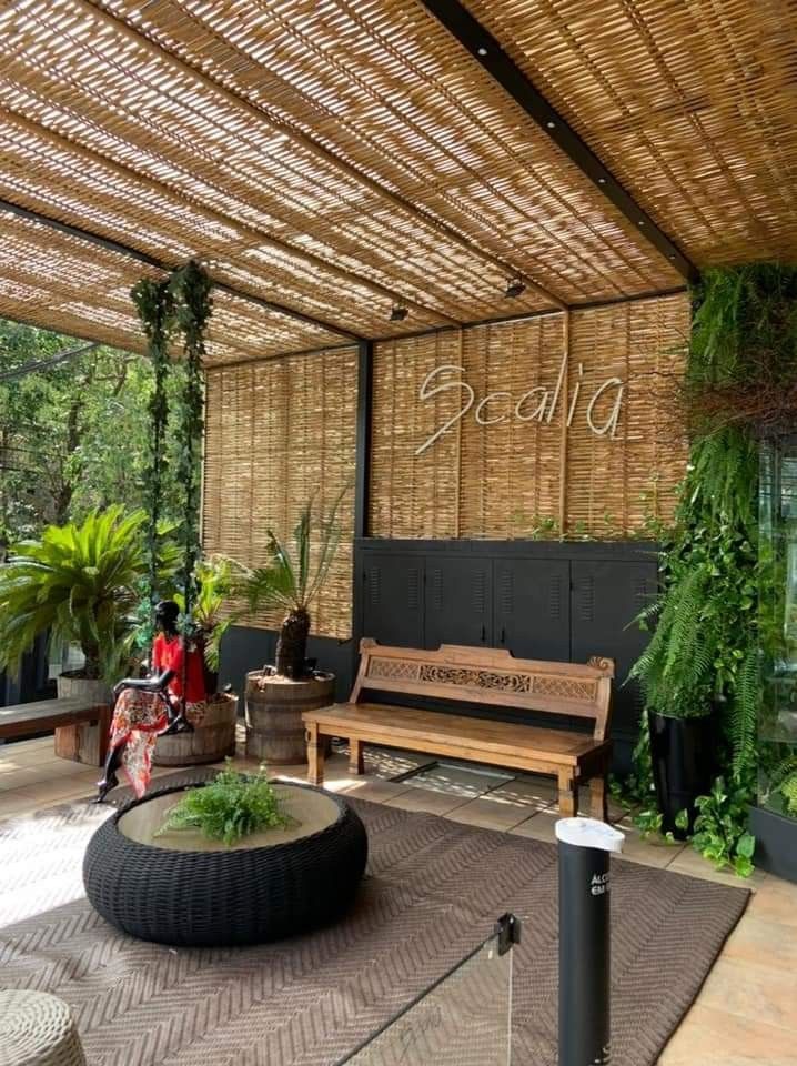 a wooden bench sitting on top of a patio next to a plant filled area with potted plants