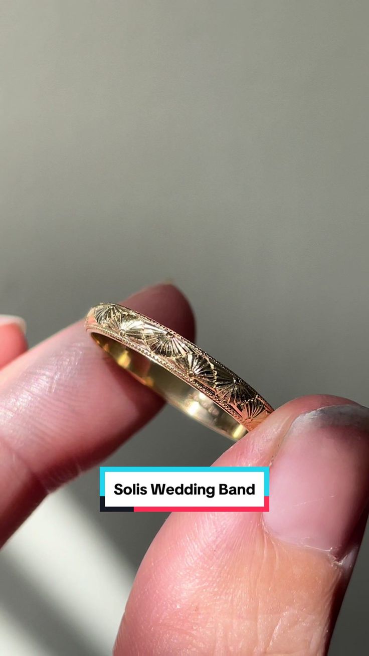 a person holding a gold wedding band in their hand with the words solis wedding band on it