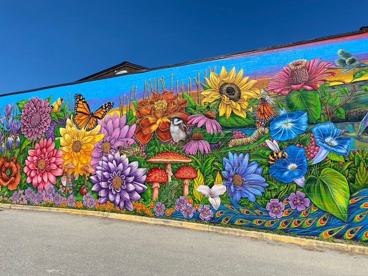 a mural painted on the side of a building with lots of flowers and birds in it