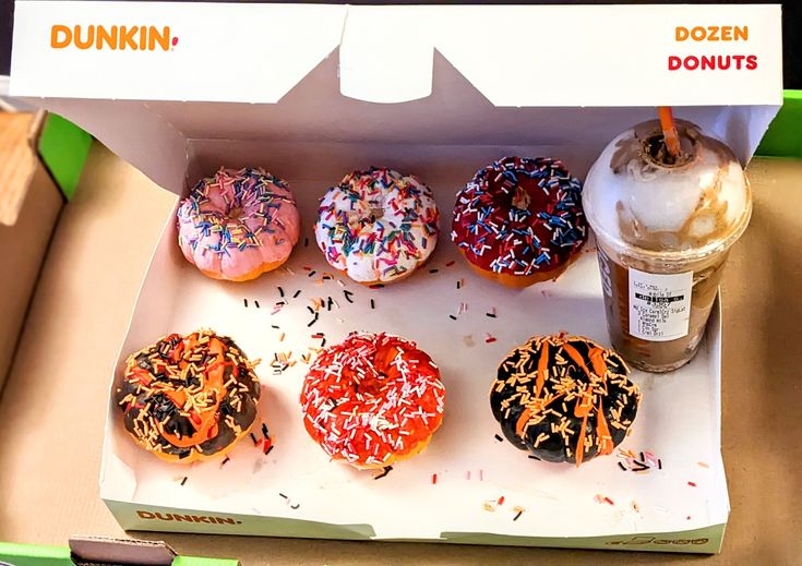 an open dunkin donuts box with six different flavored donuts and a drink