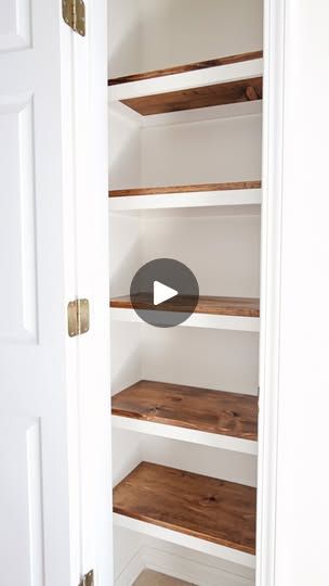 an open closet with shelves and wood flooring on the inside, in front of a white door