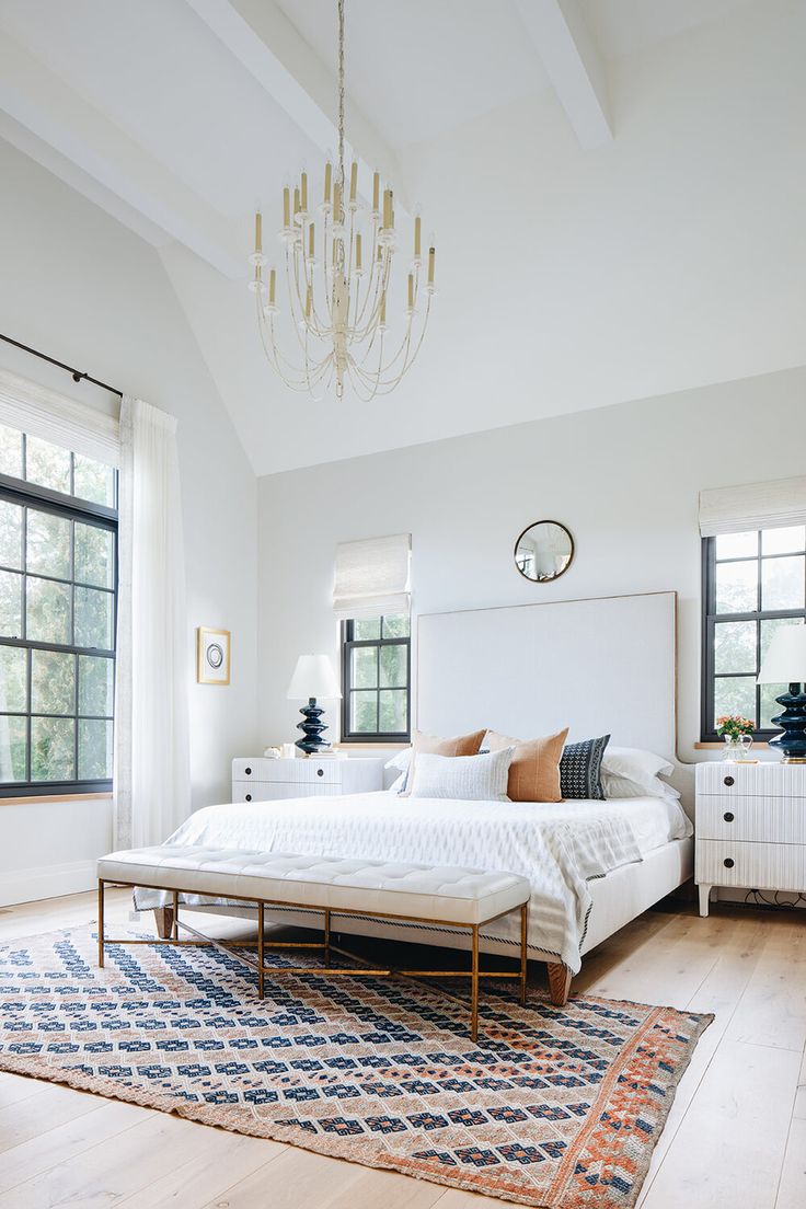 a bedroom with white walls and wooden floors has a chandelier hanging from the ceiling