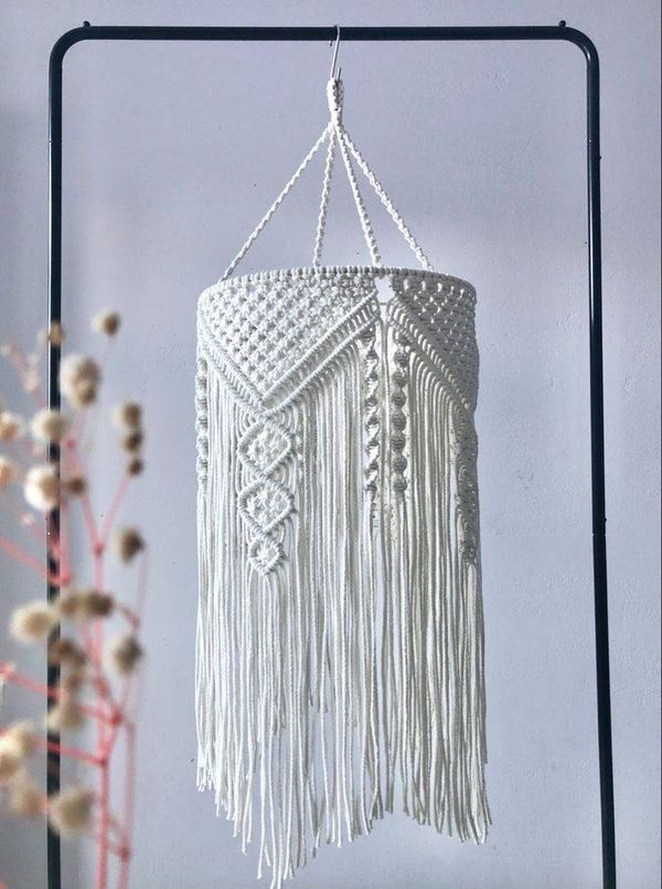 a white macrame hanging from a metal frame