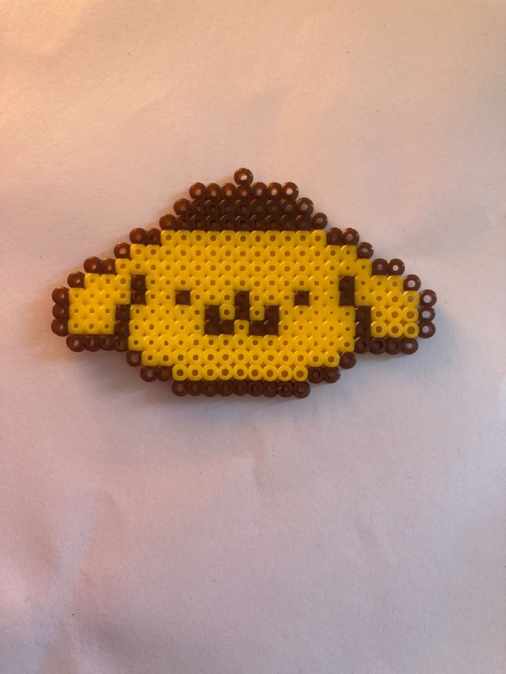 a yellow and brown beaded brooch sitting on top of a white tablecloth