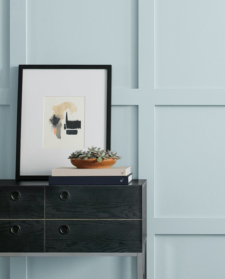 a black dresser with a potted plant on top and a framed photograph above it