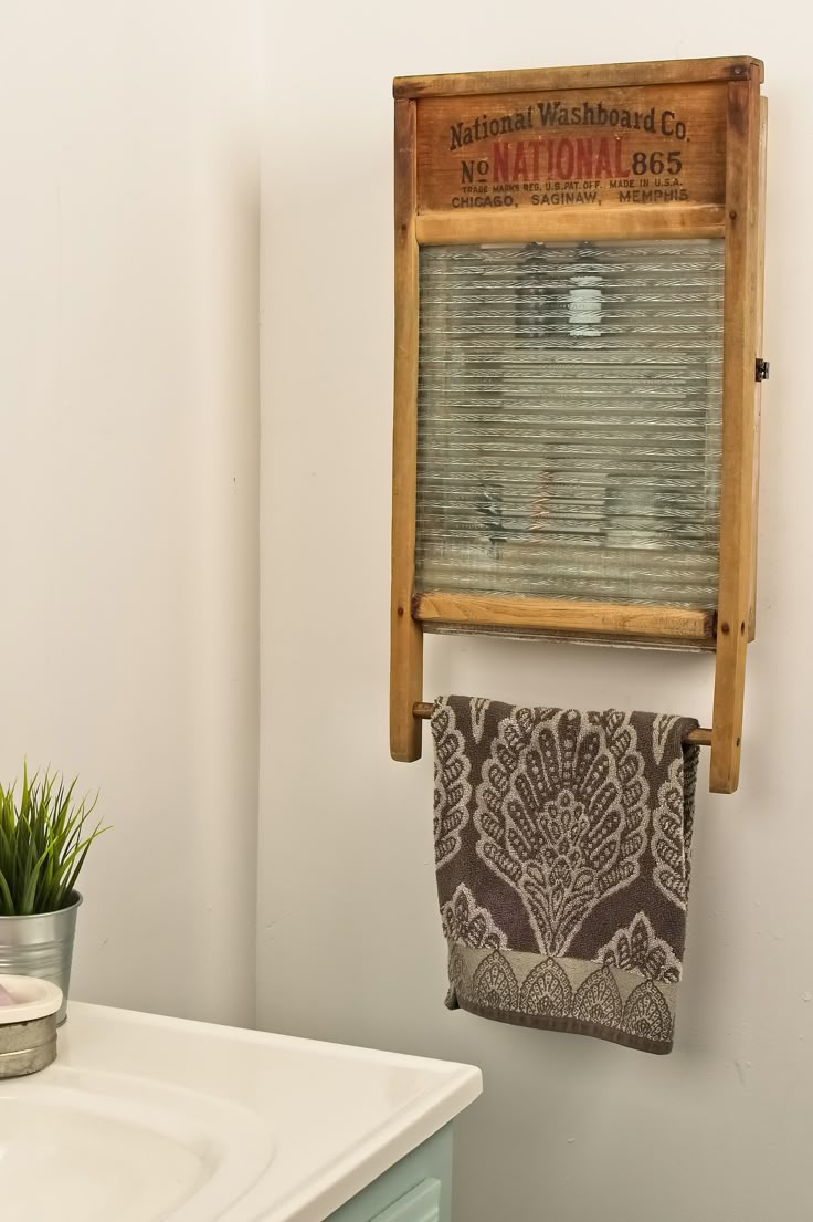 a bathroom with a wooden towel rack on the wall and a potted plant next to it