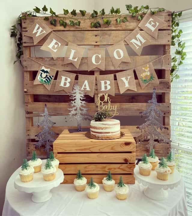 a welcome baby sign and cupcakes on a table in front of a wooden pallet