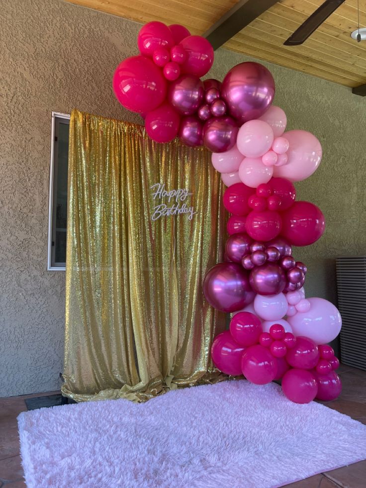 the balloon column is decorated with pink and purple balloons, along with gold drapes