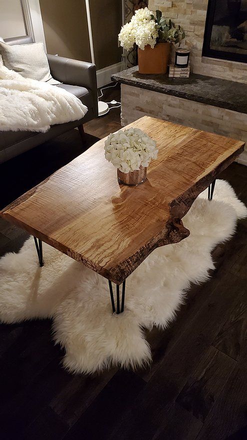 a wooden table sitting in front of a fireplace with white fur on the floor next to it