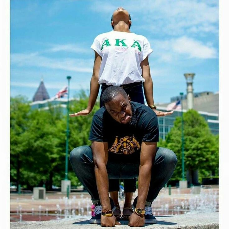 two people standing on top of each other in front of a fountain with water spouting from it