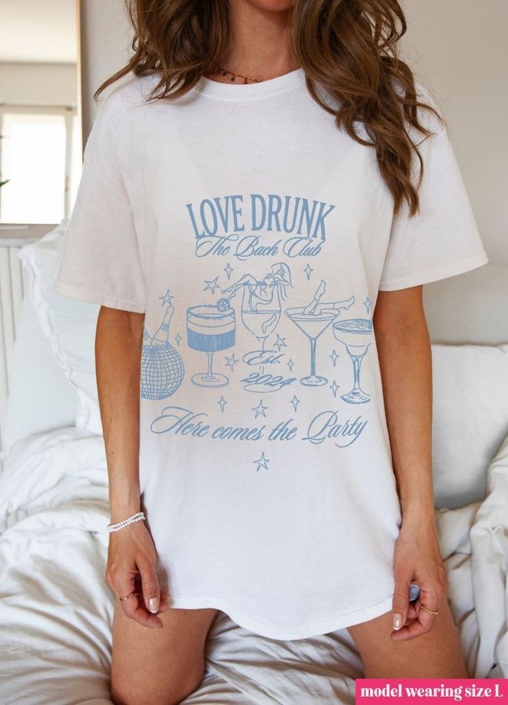 Raise a glass to love with this trendy "Love Drunk" tee. Perfect for celebrating the bride-to-be, this playful top is a must-have for any bachelorette party. Let the good times roll! Don't forget grab the matching shirt for the Bride-to-Be! Casual Graphic T-shirt For Bachelorette Party, Summer Party T-shirt With Slogan, Casual Short Sleeve T-shirt For Bachelorette Party, Casual Graphic Print T-shirt For Bachelorette Party, White Summer Top For Hen Party, White T-shirt For Bachelorette Party In Summer, White Graphic Print T-shirt For Bachelorette Party, White Short Sleeve T-shirt For Bachelorette Party, White Casual T-shirt For Bachelorette Party