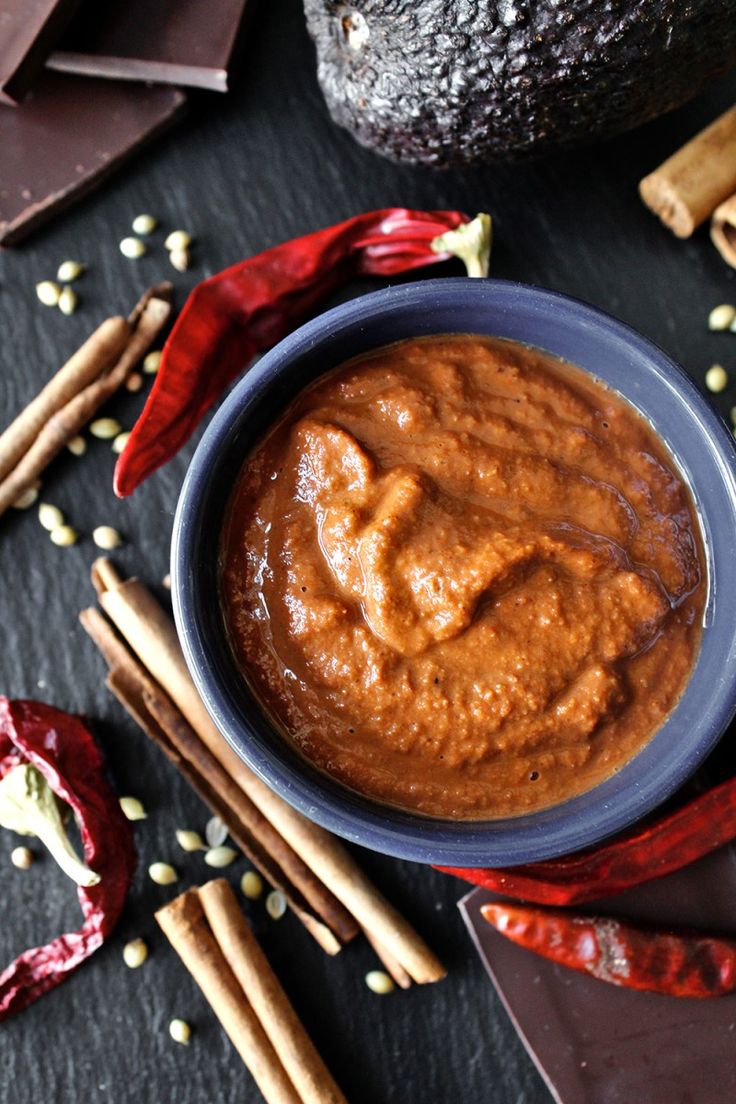 a bowl filled with peanut butter next to some cinnamon sticks and other food on a table