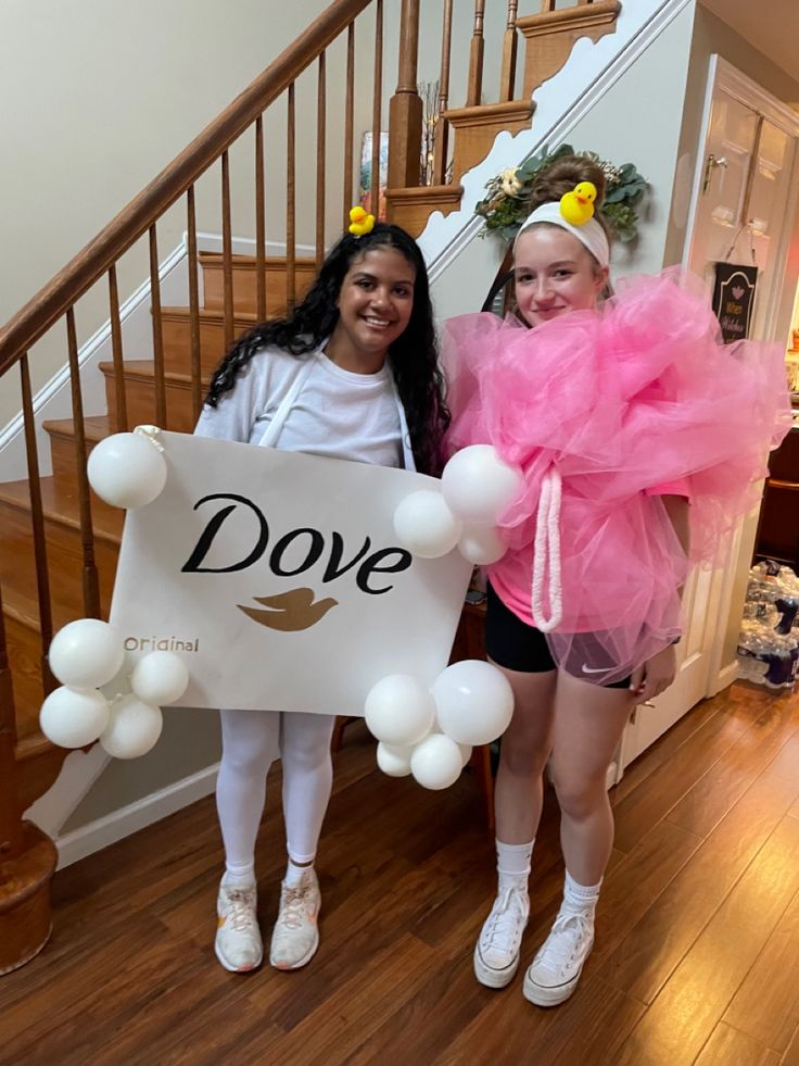 two girls dressed in costumes standing next to each other holding a sign that says dove