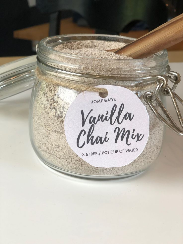 a jar filled with vanilla chai mix next to a wooden spoon on top of a table