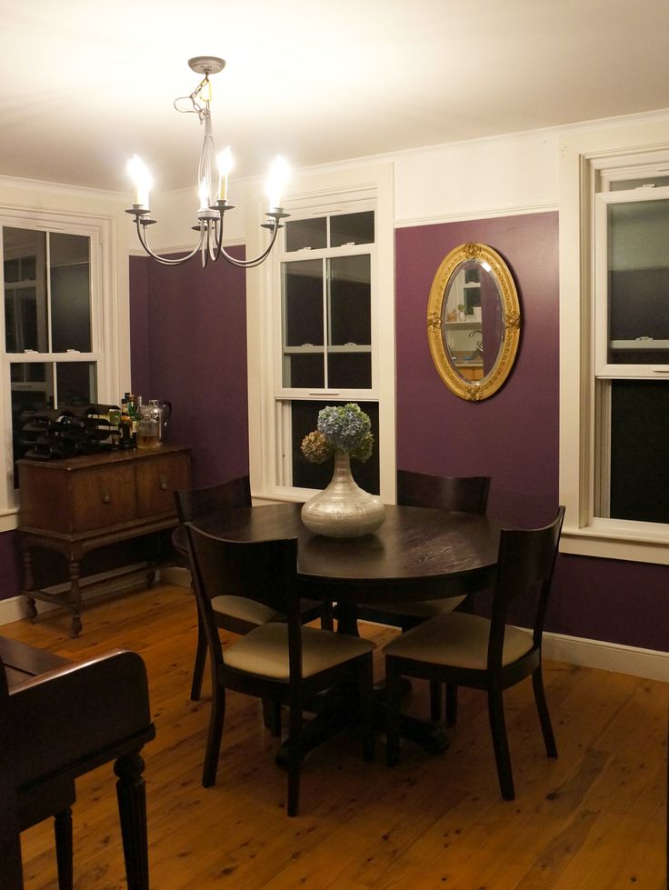 a dining room with purple walls and white trim on the windows, wooden flooring