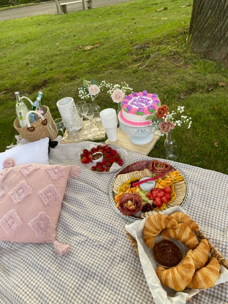 a picnic table with food and drinks on it in the middle of a grassy area