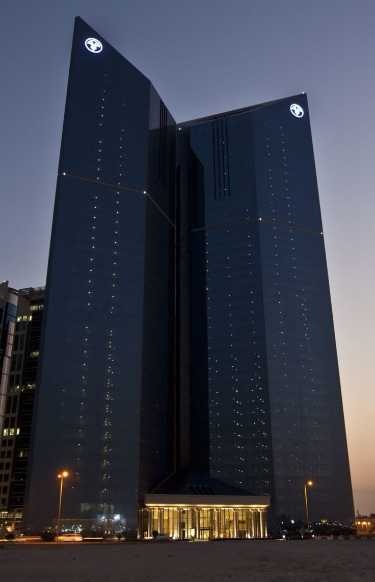 two tall buildings are lit up in the night sky with lights shining on each side