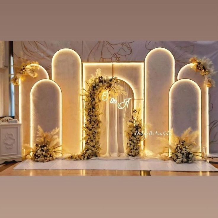 an archway decorated with flowers and greenery in front of a white backdrop for a wedding