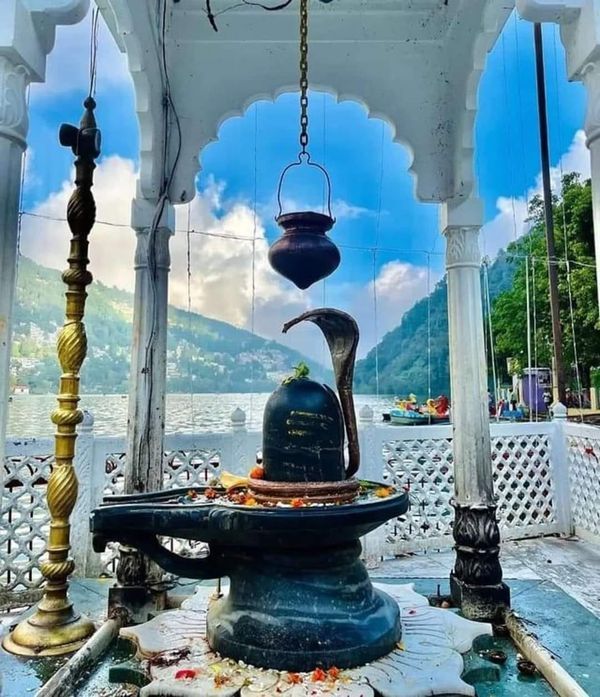 an outdoor fountain in the middle of a body of water with mountains in the background