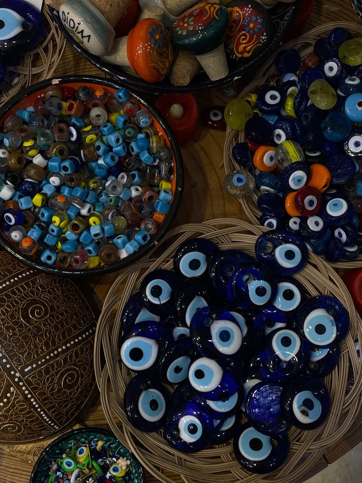 several bowls filled with lots of different kinds of glass eyeballs on top of a table