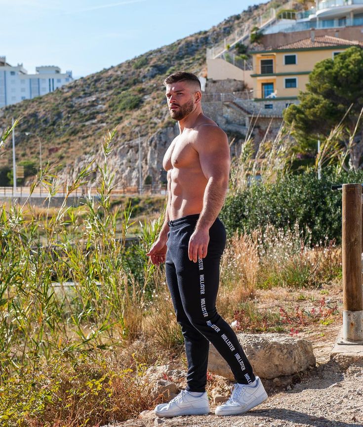 a shirtless man with no shirt standing on the side of a road in front of some buildings