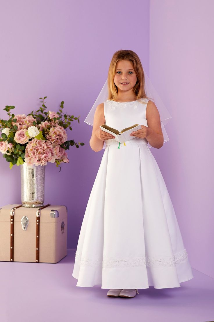 Siobhan is an elegant sleeveless ankle length Holy Communion dress. The duchess satin bodice has a beaded waistband with a matching neckline and skirt panel. The duchess satin skirt has inverted pleats to the centre. The dress is fastened with decorative fabric covered buttons, over a hidden zip at the back. It is also fully lined for maximum comfort. Available in White Shown with the Elsa Bag, Agnes Glove and Jade Headband DETAILS. Material: Outer: 100% Polyester Lining: 100% Polyester Washing guide: Machine washable Neckline: Round neck Sleeves: Sleeveless Sleeveless Satin Bridesmaid Ball Gown, Sleeveless Satin Wedding Dress With Pleated Bodice, Sleeveless Gown With Satin Finish And Fitted Bodice, Sleeveless Satin Dress With Pleated Bodice For Wedding, Sleeveless Satin Wedding Gown, Satin Finish Sleeveless Gown With Fitted Bodice, Sleeveless Wedding Dress With Princess Seams, Satin Sleeveless Dress With Fitted Bodice For Wedding, Sleeveless Satin Gown With Pleated Bodice