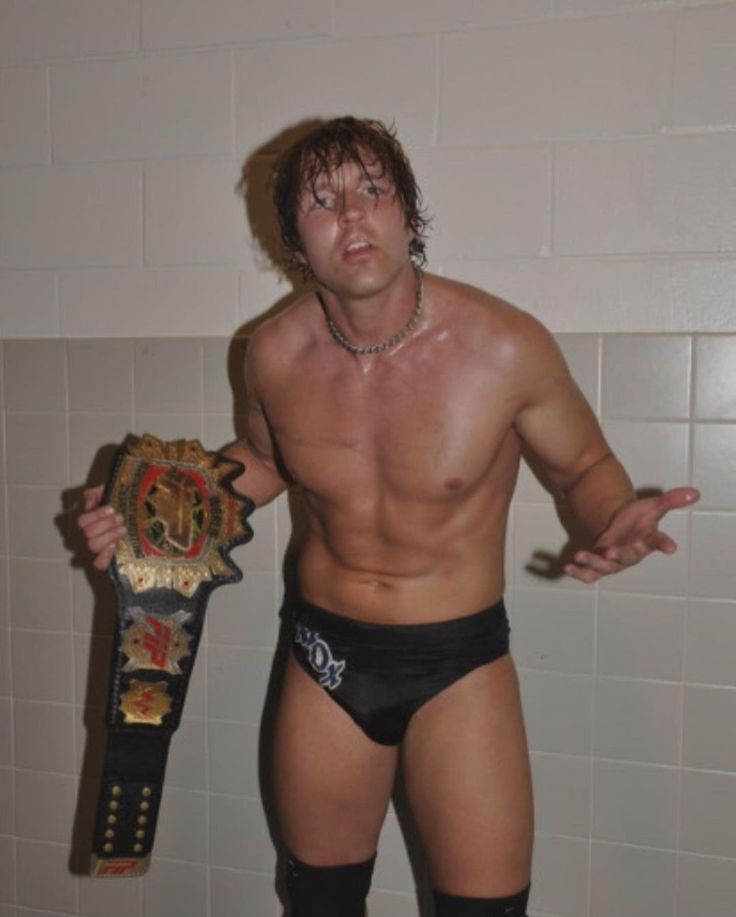 a man with no shirt holding a wrestling belt