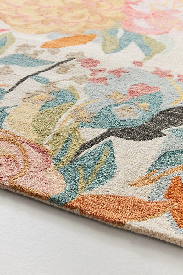 an area rug with colorful flowers and leaves on the top is laying on a white surface