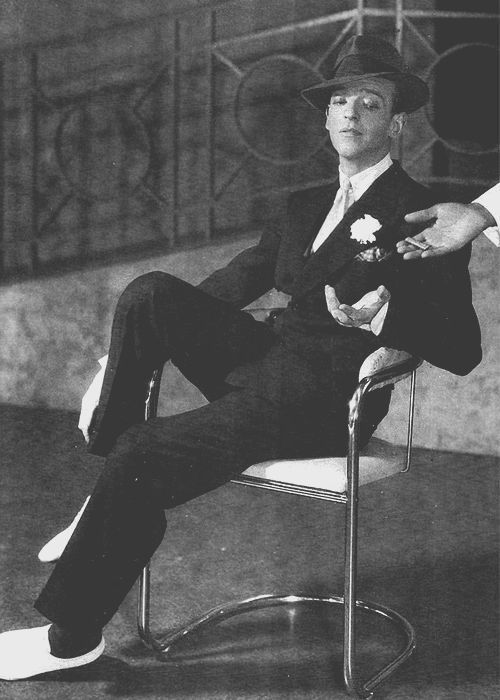 black and white photograph of a man sitting in a chair with his hand on his hip