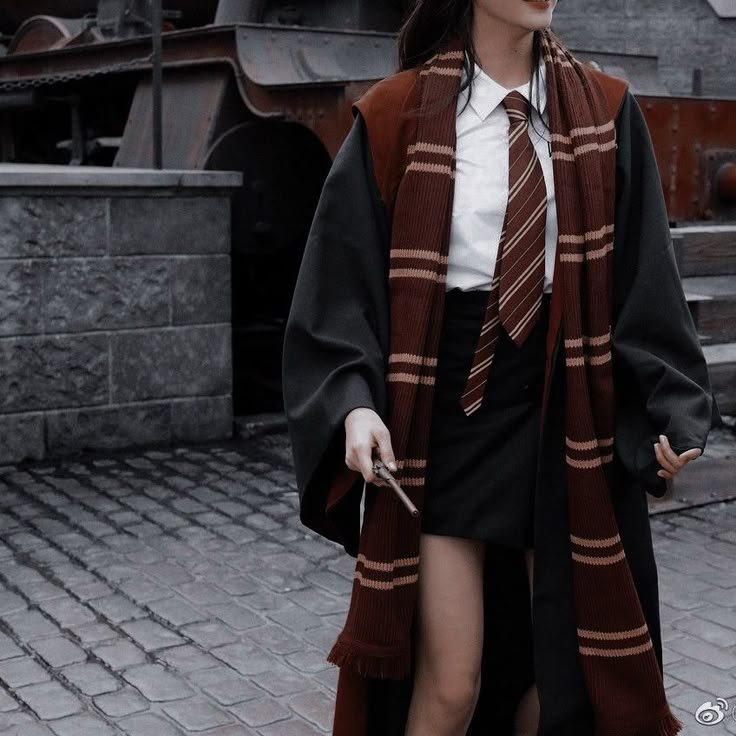 a woman wearing a scarf and skirt walking down a brick walkway in front of a train