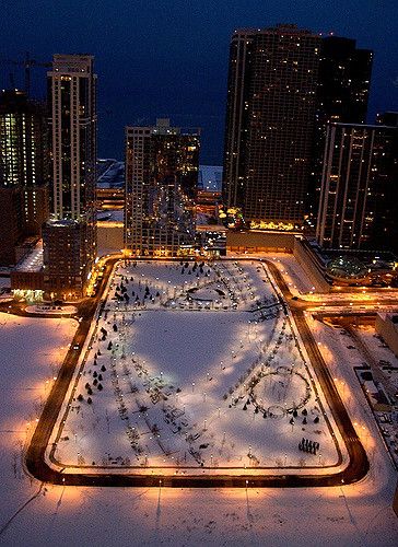 an aerial view of a city at night with snow on the ground and buildings in the background