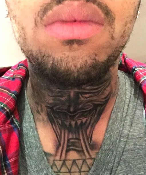 a man with tattoos on his neck and chest is looking at the camera while wearing a plaid shirt