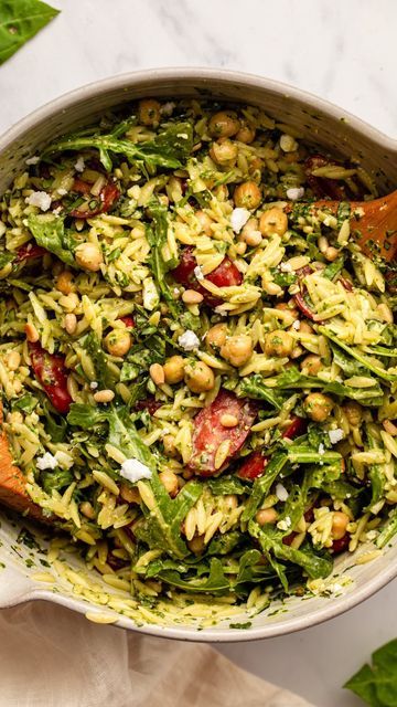 a large pot filled with lots of food on top of a white tablecloth and wooden spoon