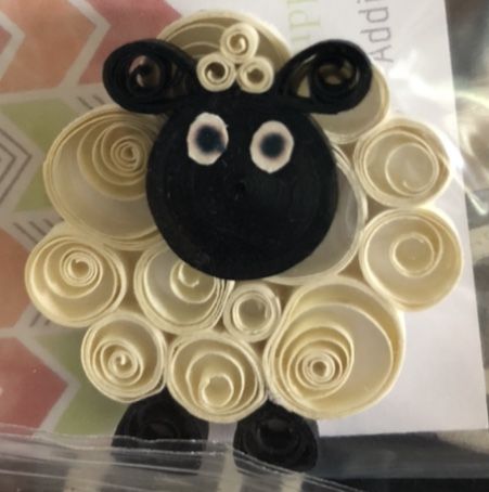 a sheep made out of rolled paper sitting on top of a plastic bag with buttons