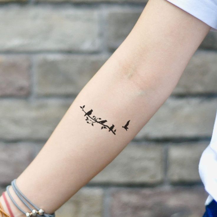 a woman's arm with a small tattoo of birds flying over the top of it