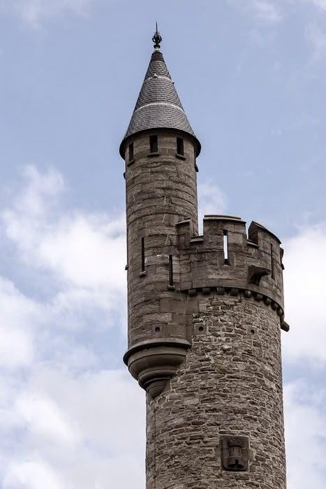 an old stone tower with a clock on it's side against a blue sky