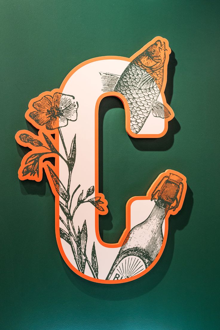 the letter c is decorated with flowers and fish on it's back side in orange and white