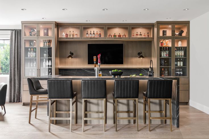 a kitchen with an island, bar and chairs in front of the tv on the wall