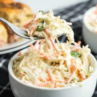 a white bowl filled with coleslaw on top of a black and white checkered table