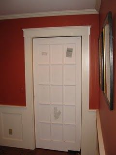 a white door in the corner of a room with red walls and wood flooring