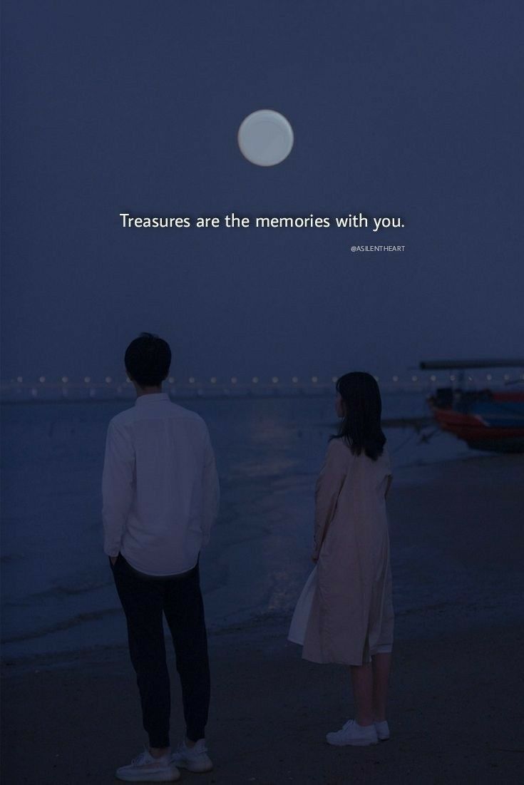 two people standing on the beach looking out at the water with a full moon in the background