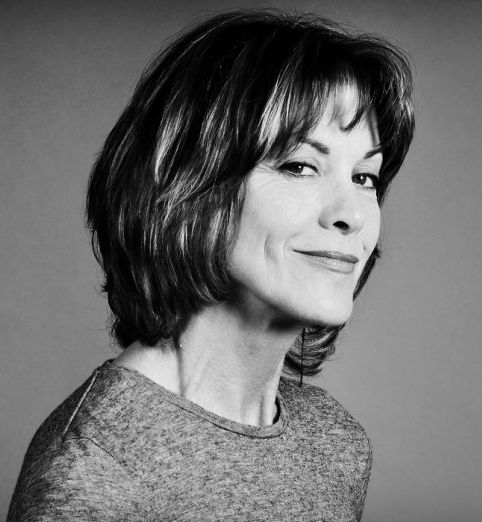 a black and white photo of a woman with shoulder length hair smiling at the camera