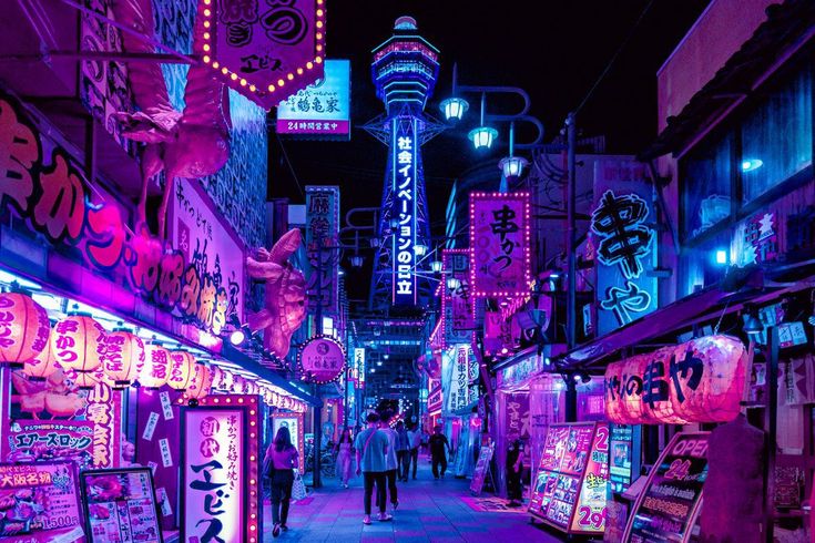 people walking down an alley at night with neon signs on the walls and buildings in the background