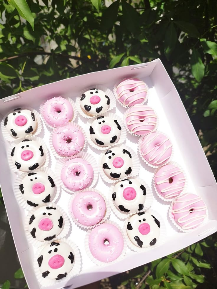 a box filled with lots of pink and white donuts on top of a table