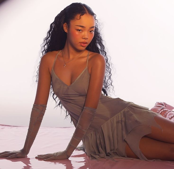 a beautiful young woman sitting on top of a pink floor