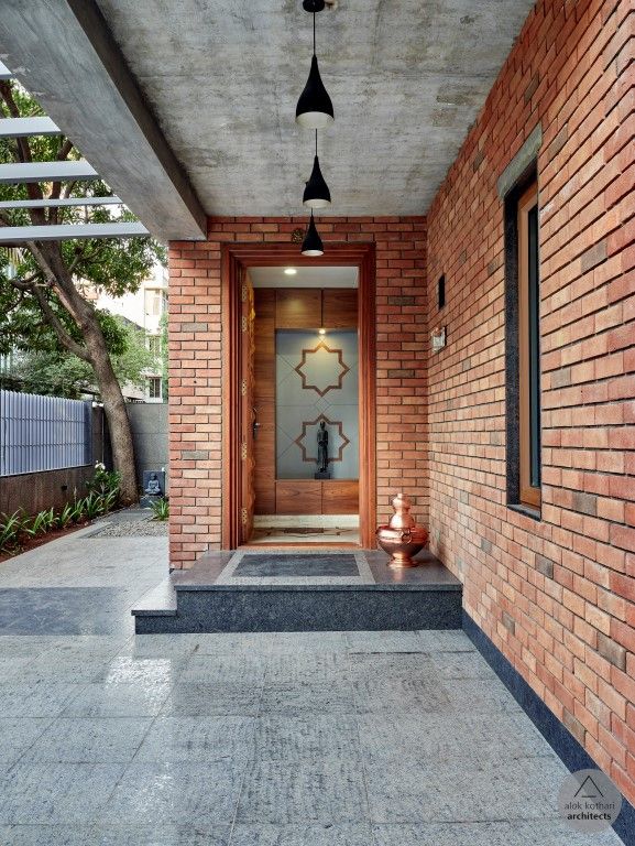 an entry way with brick walls and steps leading up to the front door is lit by two pendant lights