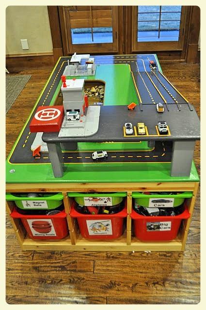 a toy train table with lots of storage bins on it and some toys in the middle