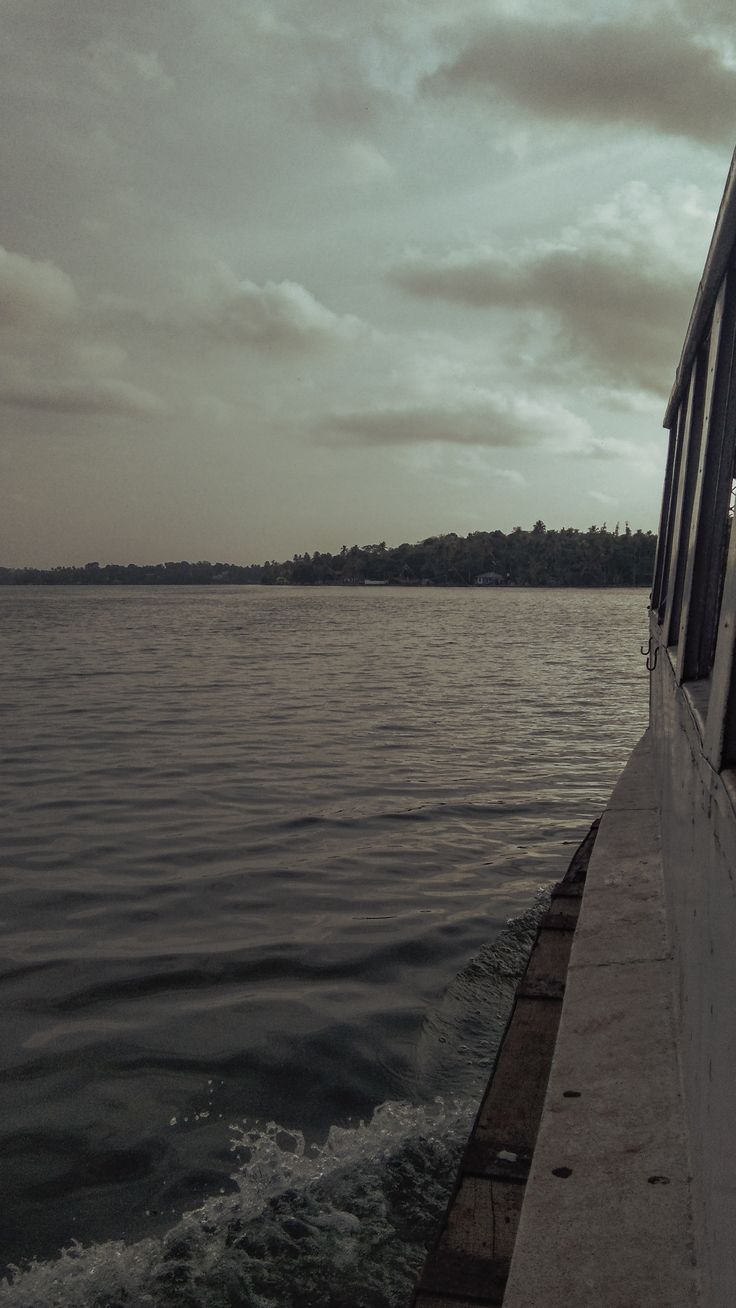 the back end of a boat traveling across a large body of water on a cloudy day